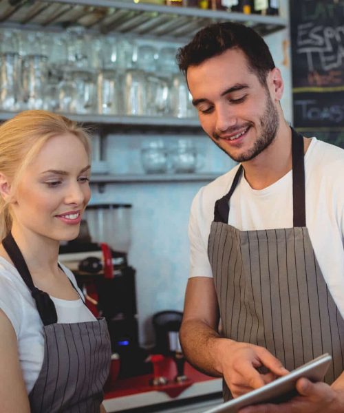 Nem Booking til café To cafémedarbejdere som benytter Nem Booking bordbookingsystem på tablet
