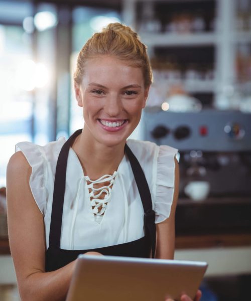 Nem Booking på iPad Kvindelig cafémedarbejder står og smiler med Nem Booking bordbookingsystem på tablet